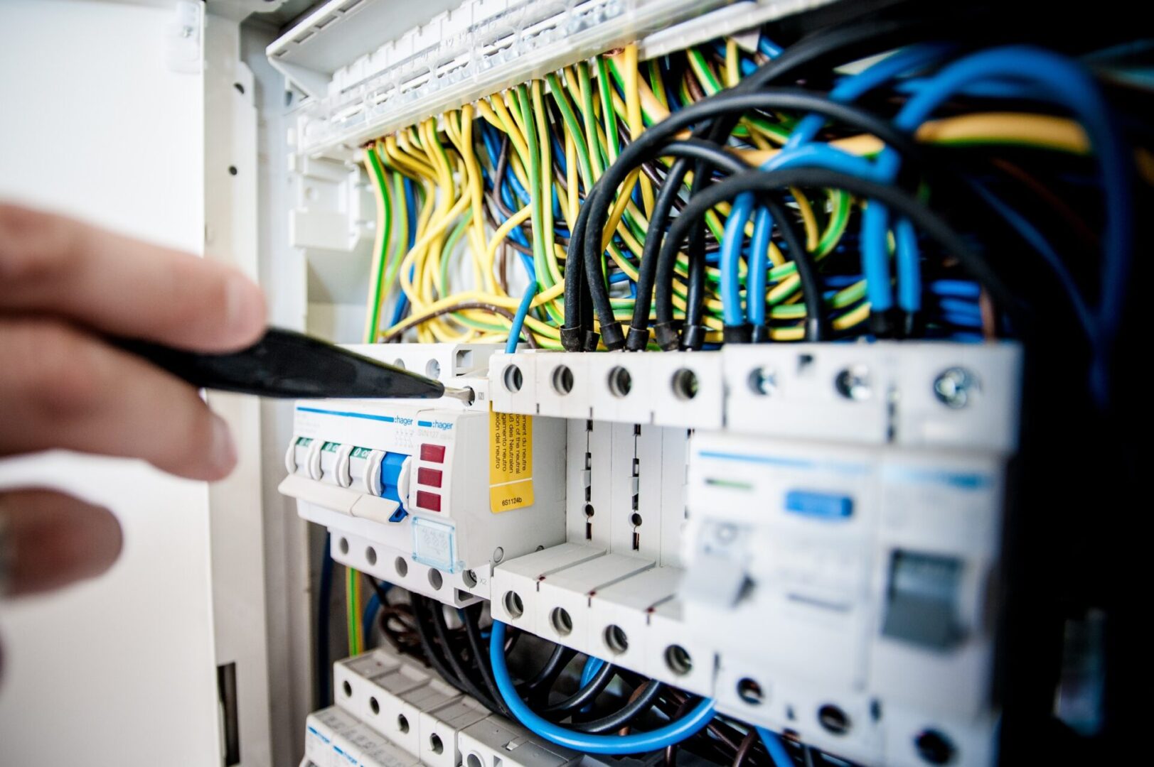 A person is holding a remote control in front of wires.